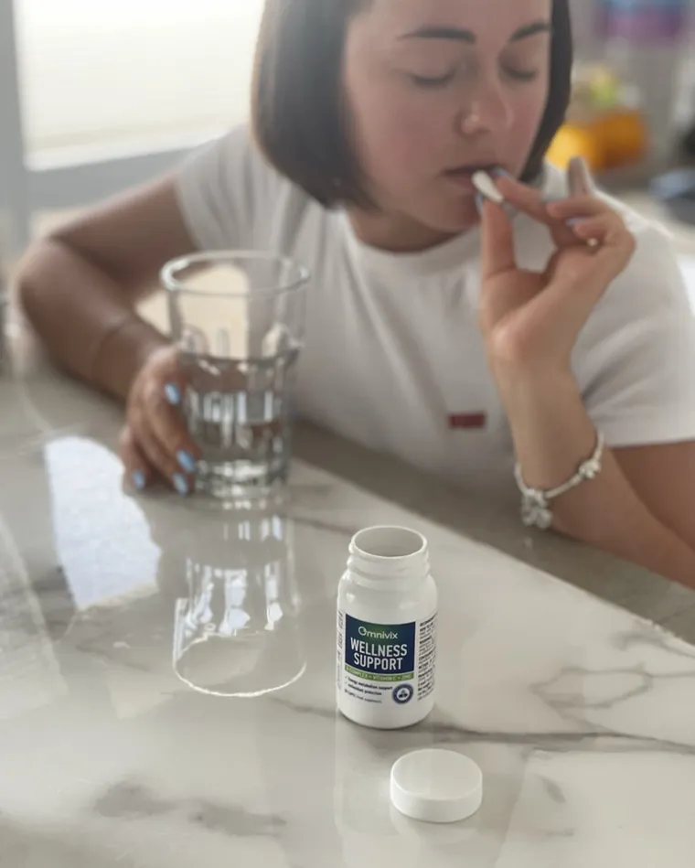 Donna che assume una capsula di Omnivix con un bicchiere d’acqua